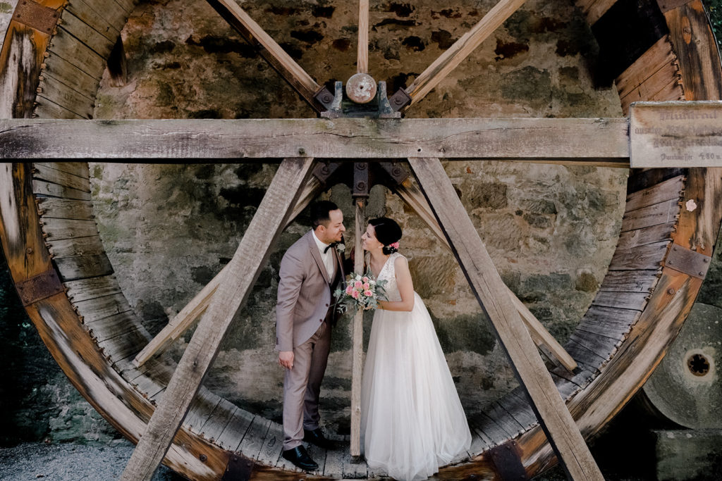 Glückliches Brautpaar, das in einem alten Mühlrad inmitten von Dinkelsbühl steht.