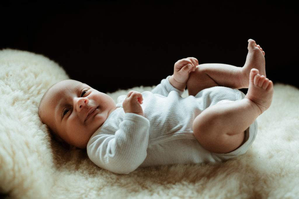 Ein Lammfell und ein Baby in weißem Strampler, mehr braucht es eigentlich nicht für wunderschöne Aufnahmen bei eurem Neugeborenen Fotoshooting.